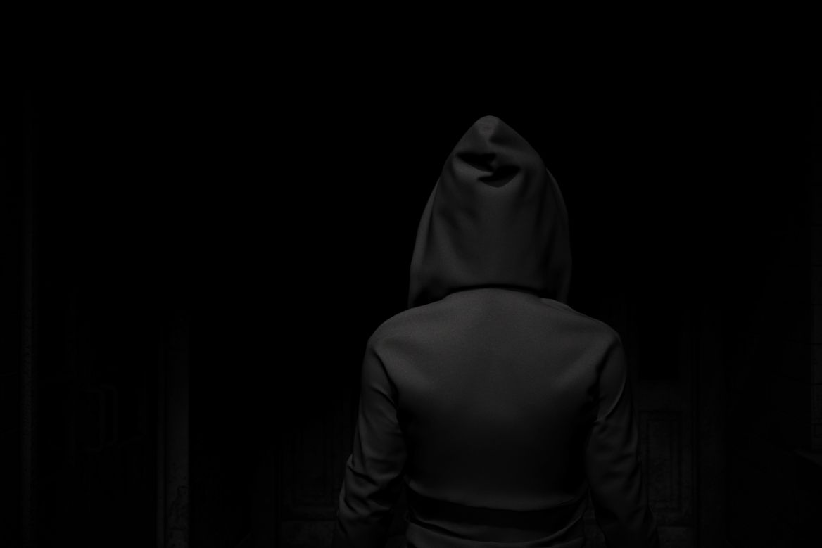 back of a hooded figure in a dark alley