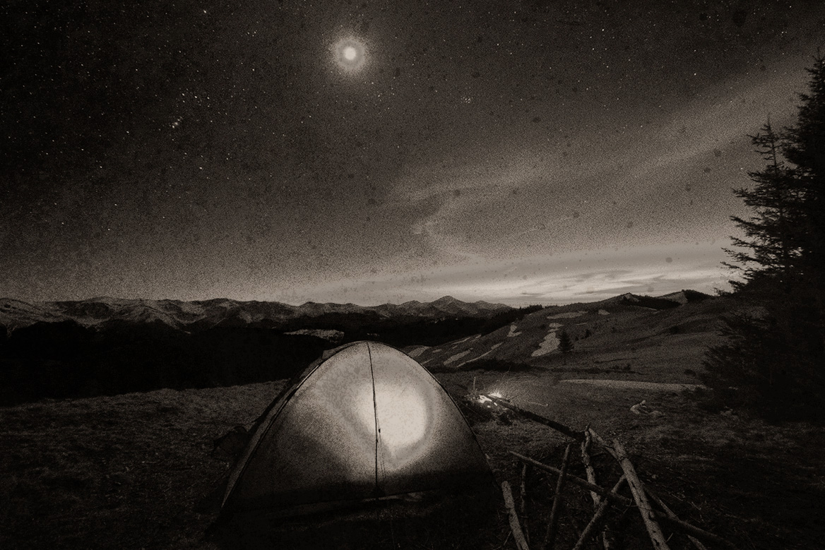 A tent set up in the vast open wilderness.