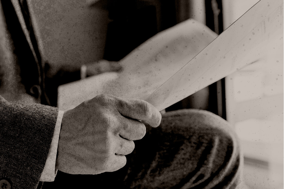 hands holding a newspaper above a man's lap